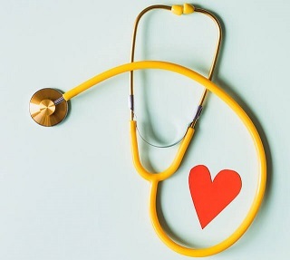 Gelbes Stethoskop mit einem roten Herz