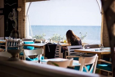 Junge Frau allein im Cafè am Meer